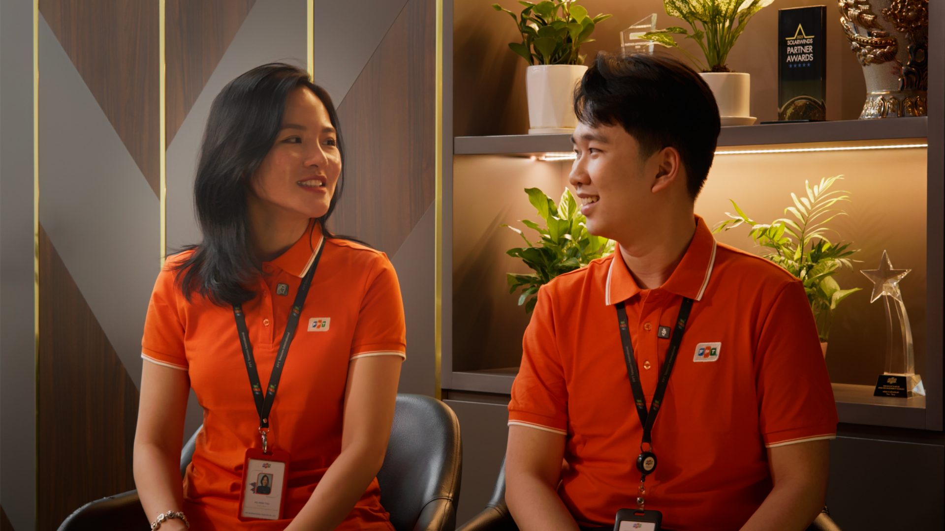 Two young FPT Telecom employees laughing together during a paired interview